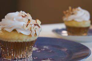 yellow cupcakes with white frosting and almond garnish on blue plates