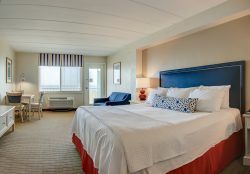 red and blue nautical oceanfront hotel room with bed sofa and dining area
