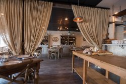 rustic restaurant with wooden tables and burlap curtains