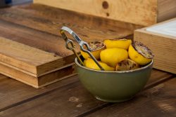 charred lemons in a bowl with tongs on a wooden butcher block