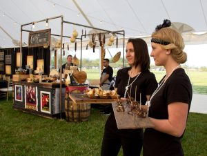 servers dressed in flapper style holding appetizers for an outdoor event