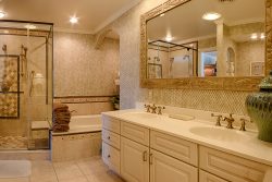 Master bathroom with gold accents two sinks large bathtub and walk in shower