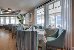 fancy oceanfront restaurant with upholstered chairs and wine glasses on table