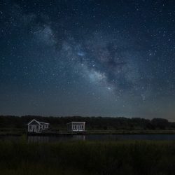 two boat houses at night with milkyway background