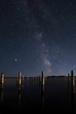 pilings in the water at night with milkyway galaxy