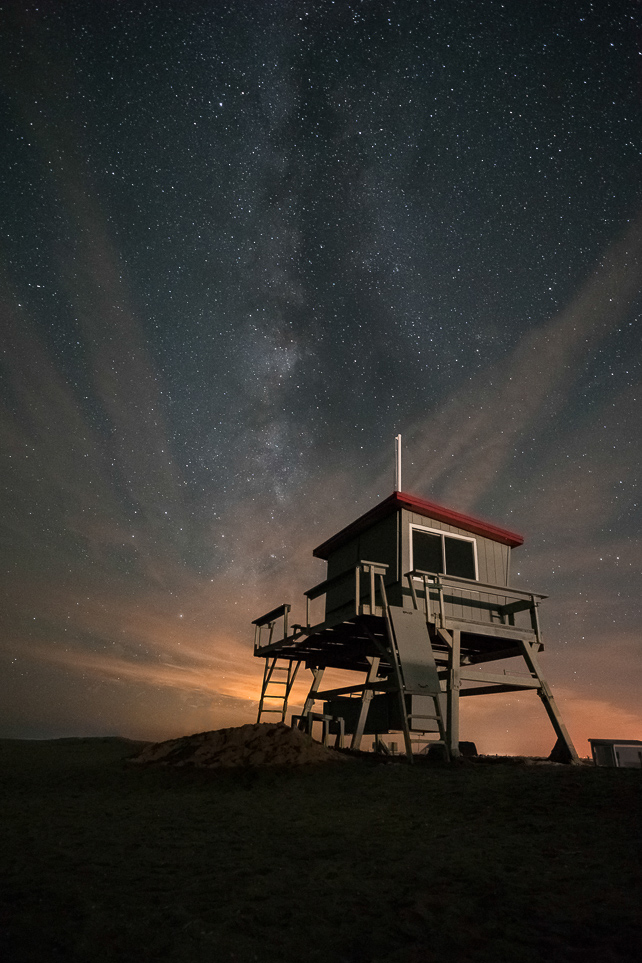 a lifeguard stand on the beach at night with stars in the sky