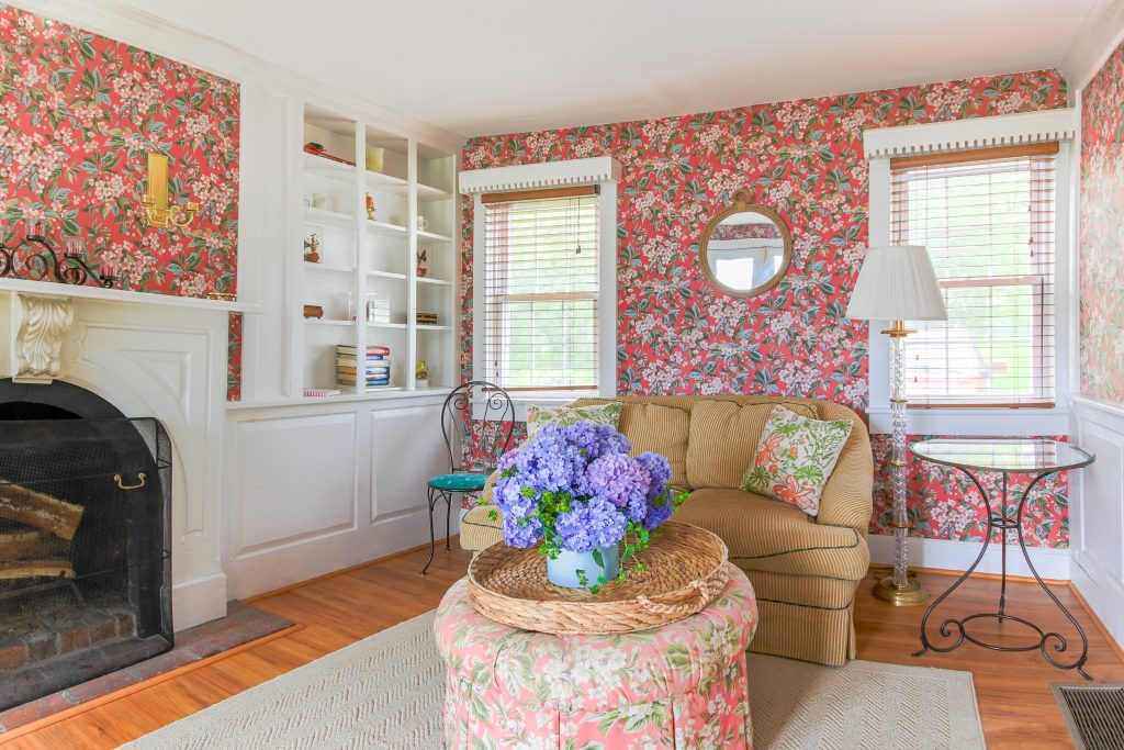 A cottage living room with floral wallpaper and a fireplace